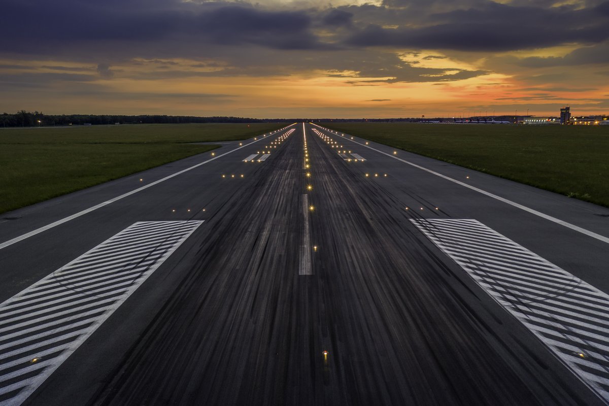 Used concrete asphalt airport empty runway with many braking marks, markings for landings and all navigation lights on. Clear for comercial airplane landing or taking off in Wroclaw airport