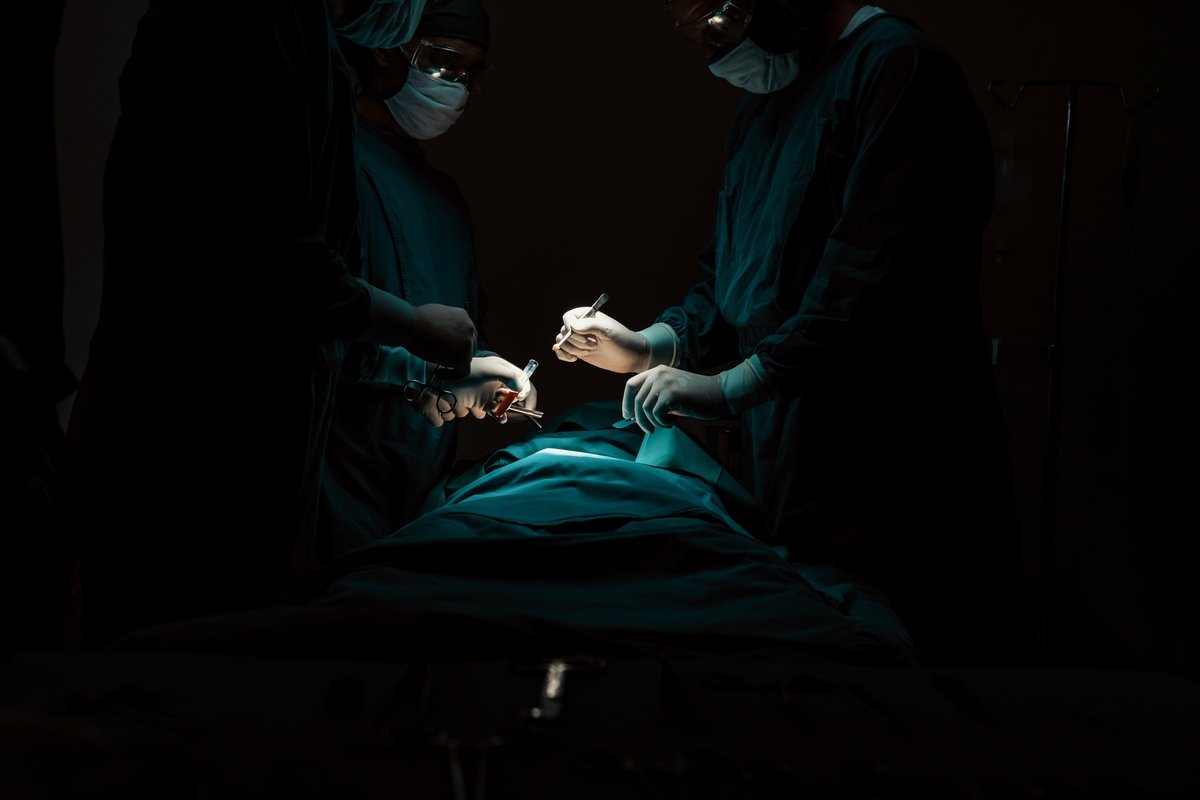Surgical team performing surgery to patient in sterile operating room.