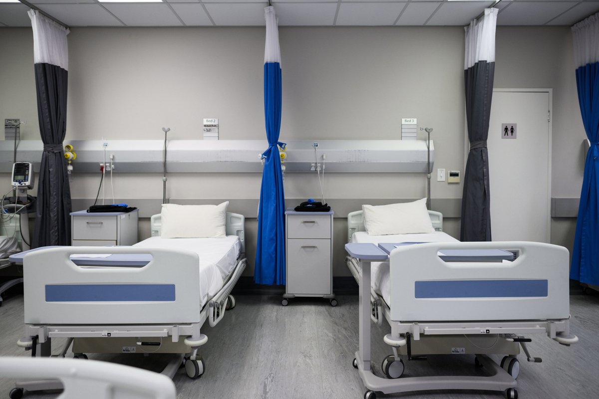 Two empty beds in hospital ward with curtains tied back neat and tidy