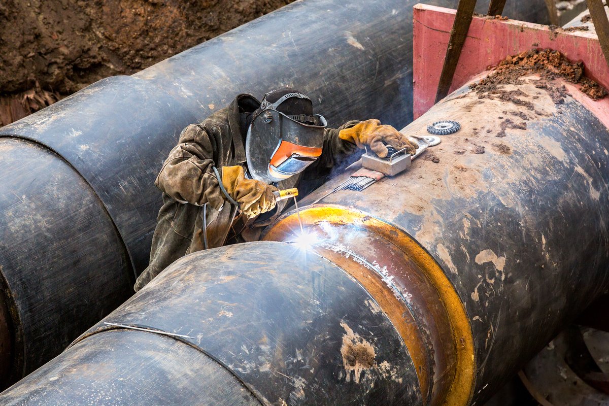 Worker with protective mask welding metal with sparks and smoke